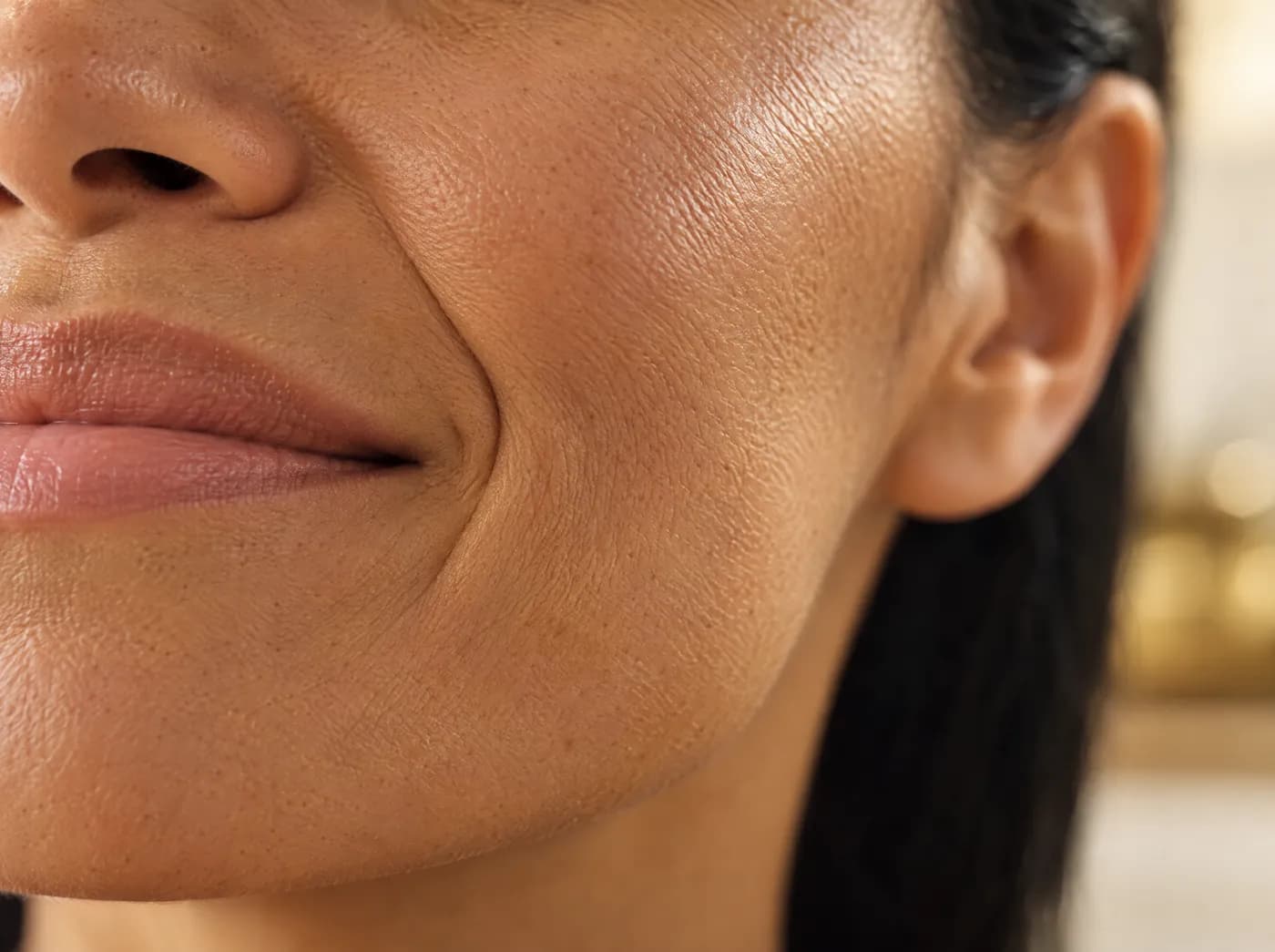 Detalle de la piel de la mejilla de una mujer adulta con textura natural, iluminada con luz suave de ventana