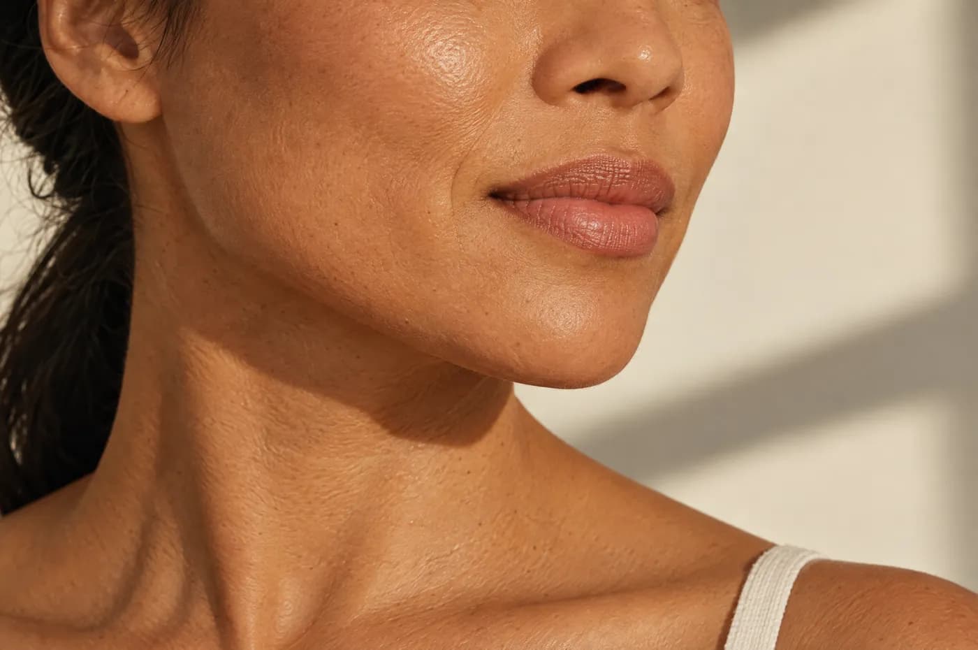 Mejilla y mandíbula de una mujer con piel luminosa y textura natural bajo luz de ventana