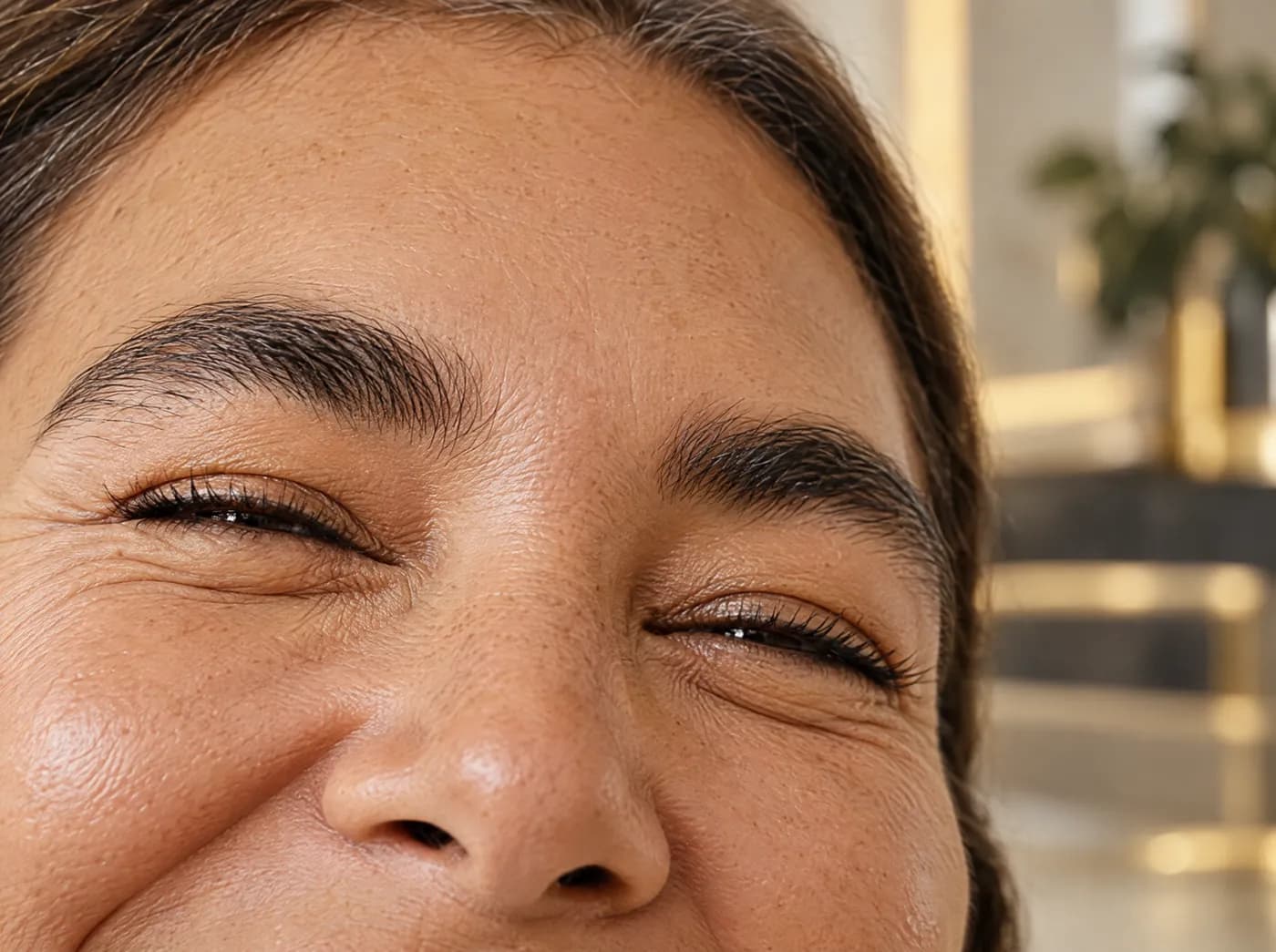 Mirada de una mujer madura sonriendo, recortada a la altura de los ojos, con líneas de expresión suaves y piel con textura real